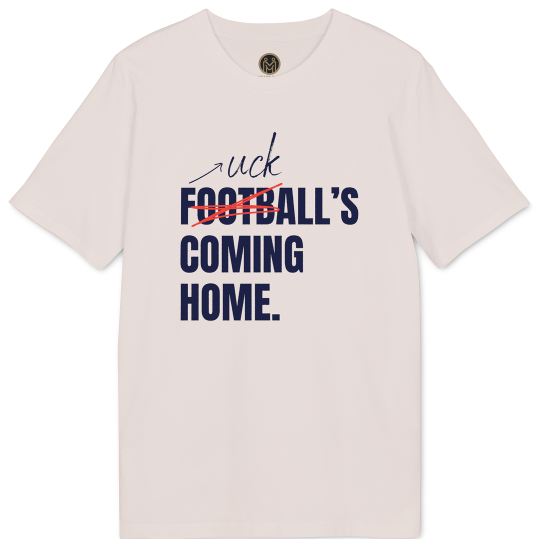 A light pink short-sleeve t-shirt with a graphic print on the front. The graphic features the word 'uck' in black script, the word 'FOOTBALL' in bold navy blue text crossed out with a red scribble, and 'COMING HOME.